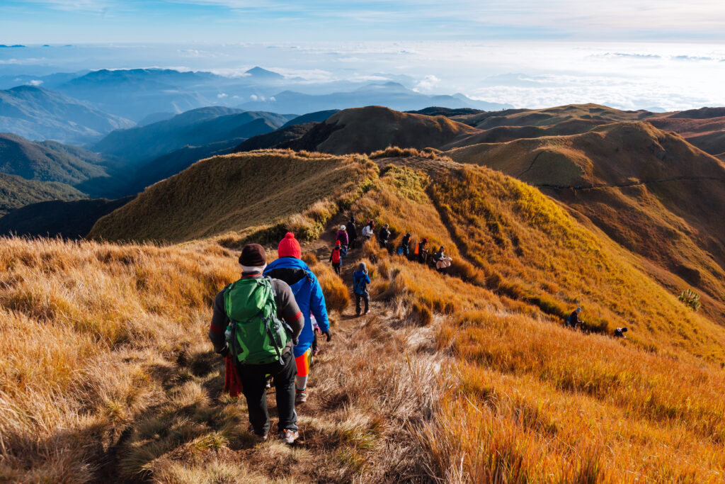 Travelers hiking to the summit of Mount Pulag, the highest peak in Luzon, Philippines. Travel to the Philippines to experience stunning natural beauty and unforgettable adventures